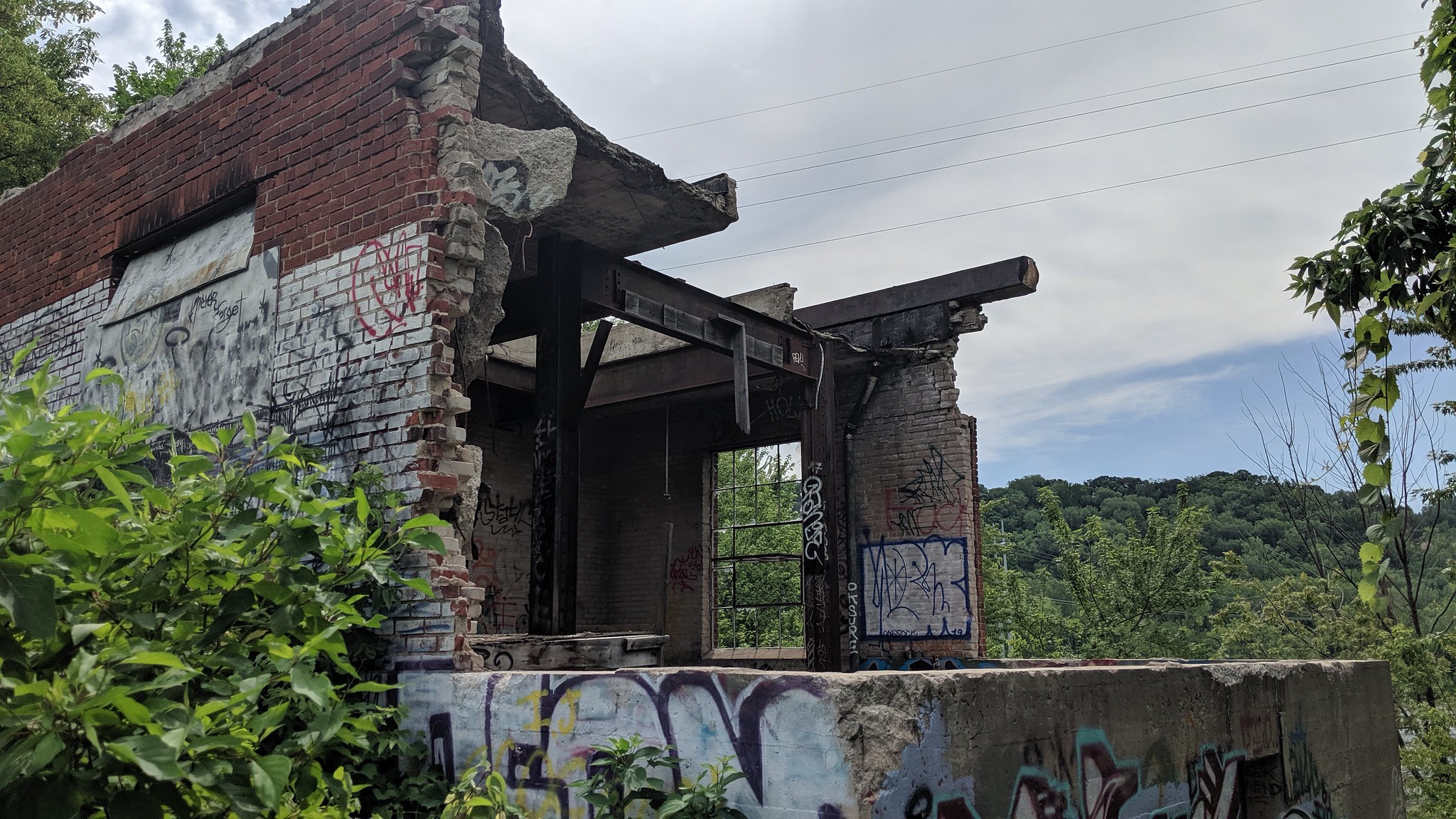 A small brick and concrete structure in significant disrepair.