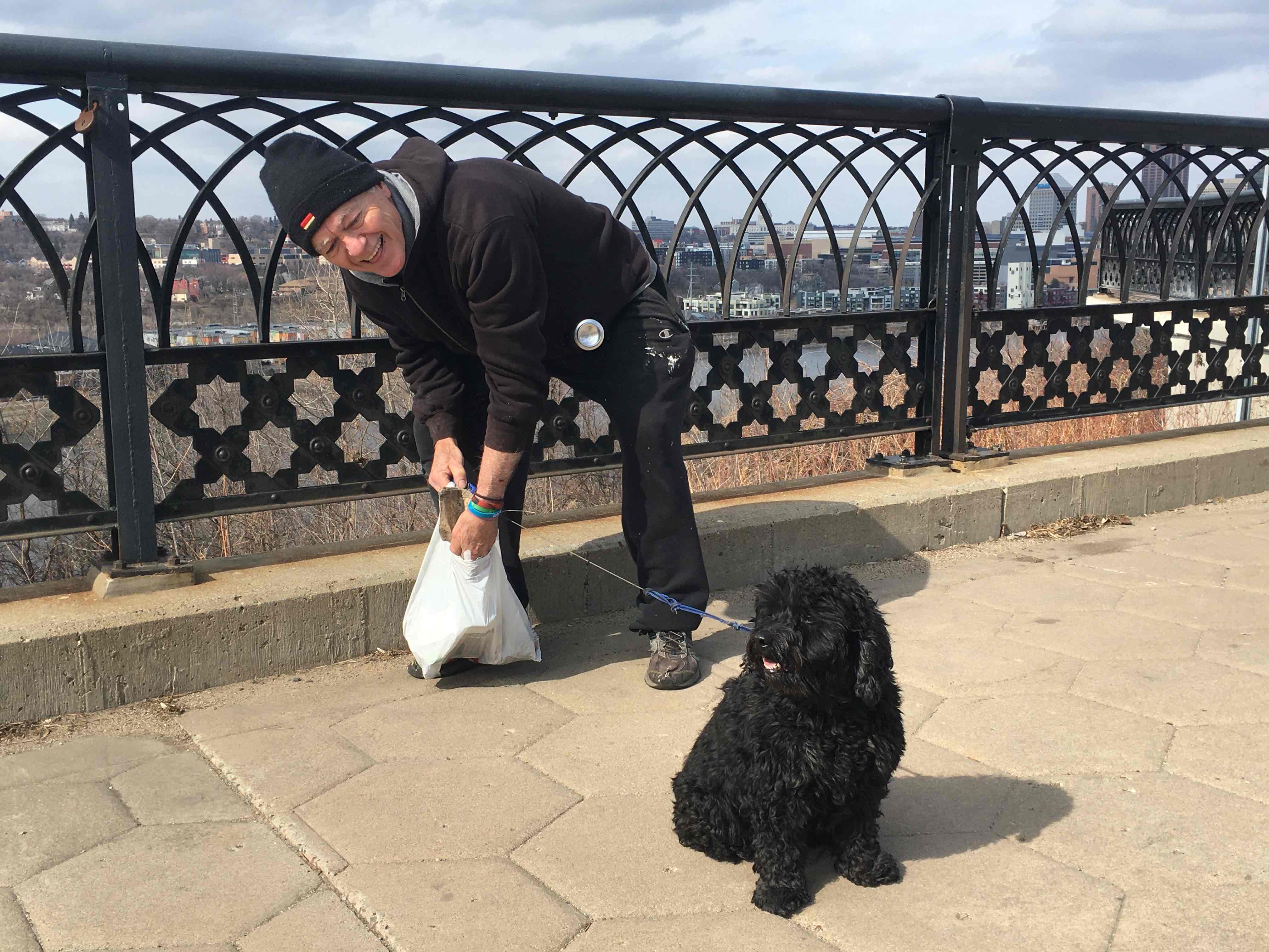 Nico the dog and his human pick up trash on a bridge over the Mississippi