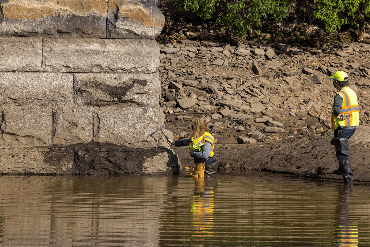 People in vests near bridge in water