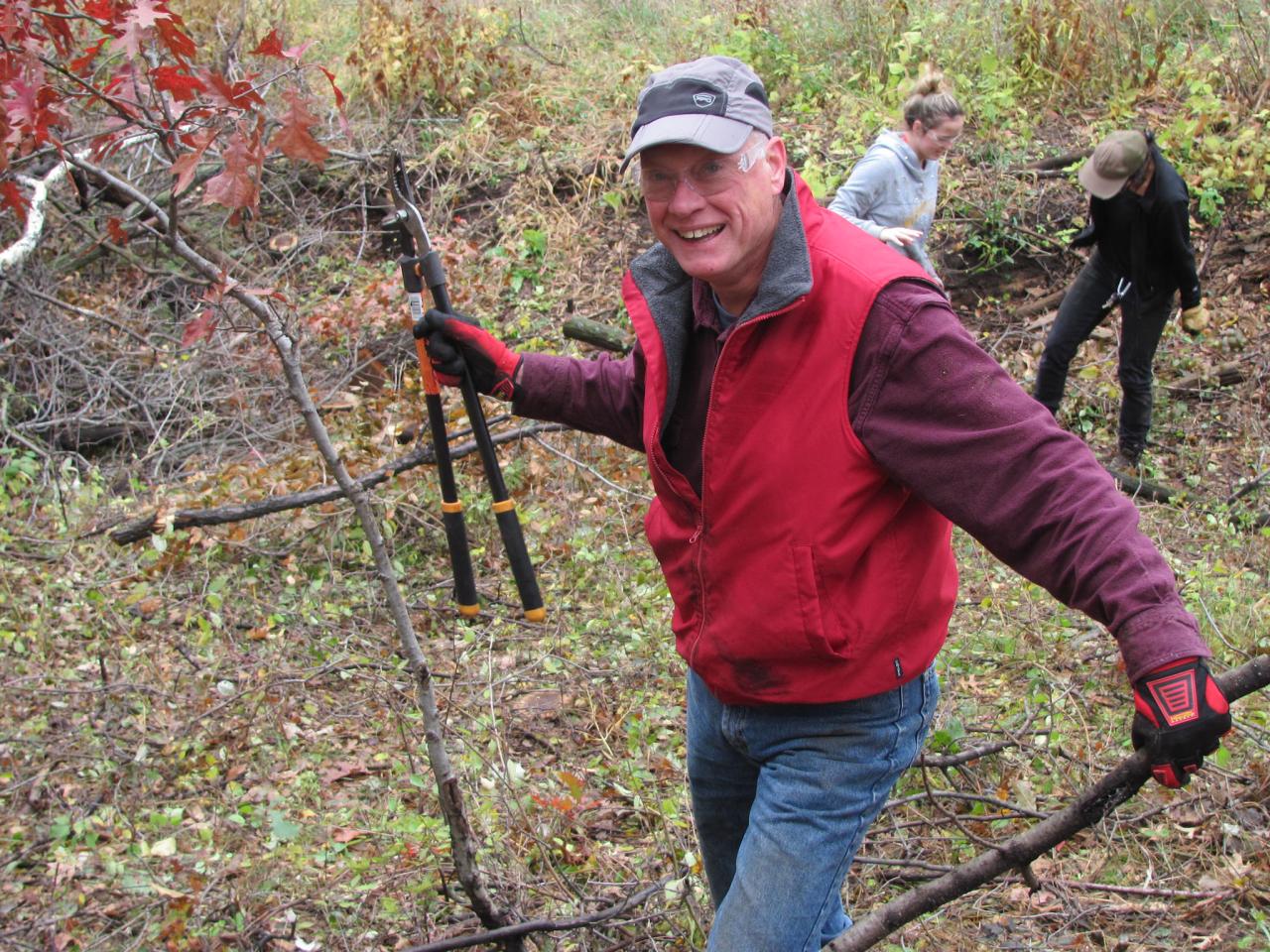 Volunteer with lopper and buckthorn in hand Volunteer with lopper and buckthorn in hand