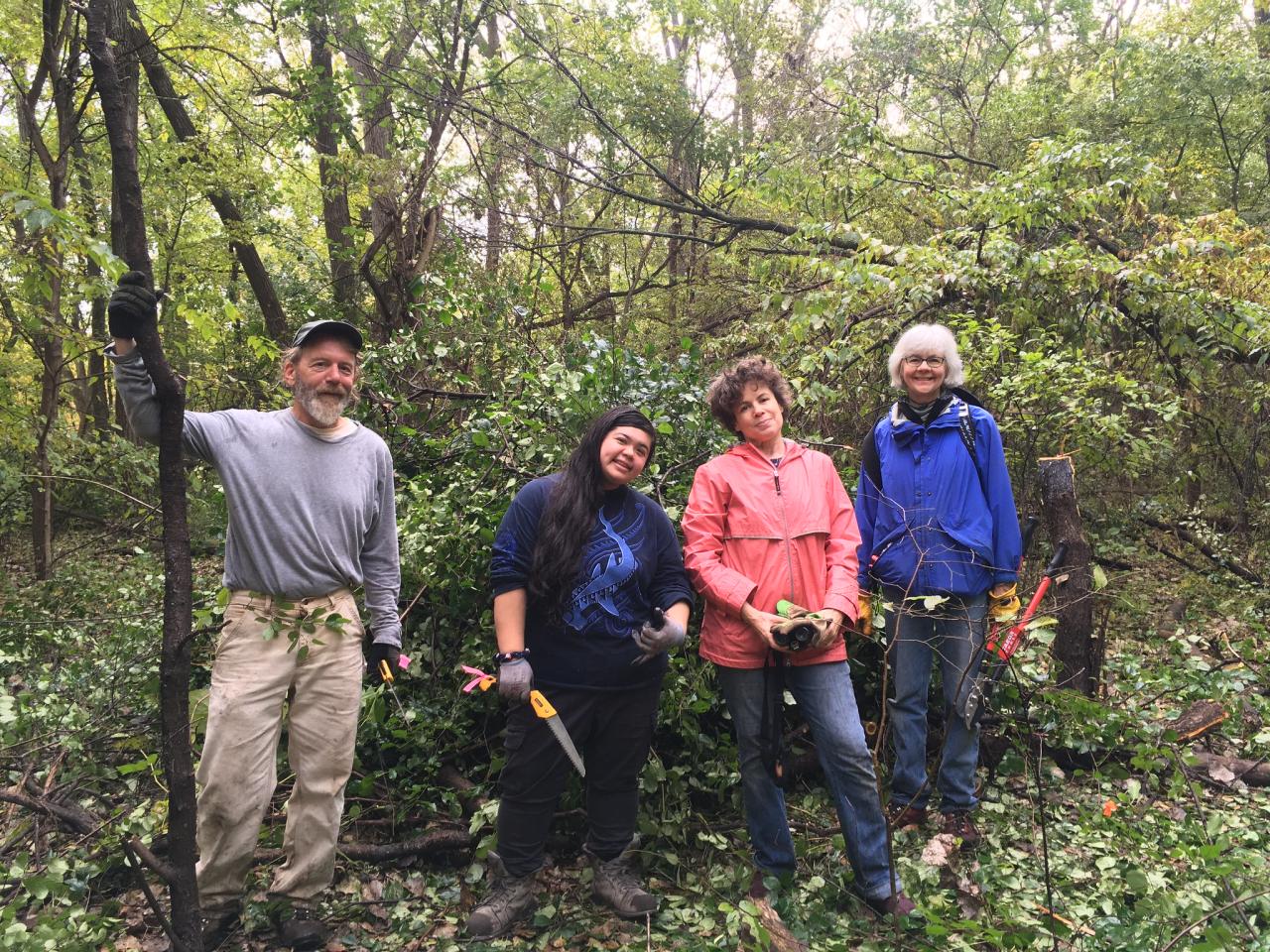 Buckthorn pile and volunteers Volunteers pose in front of cut buckthorn in the river gorge