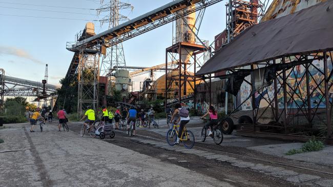 Bicyclists ride among abandoned industrial structures at the Upper Harbor Terminal site.
